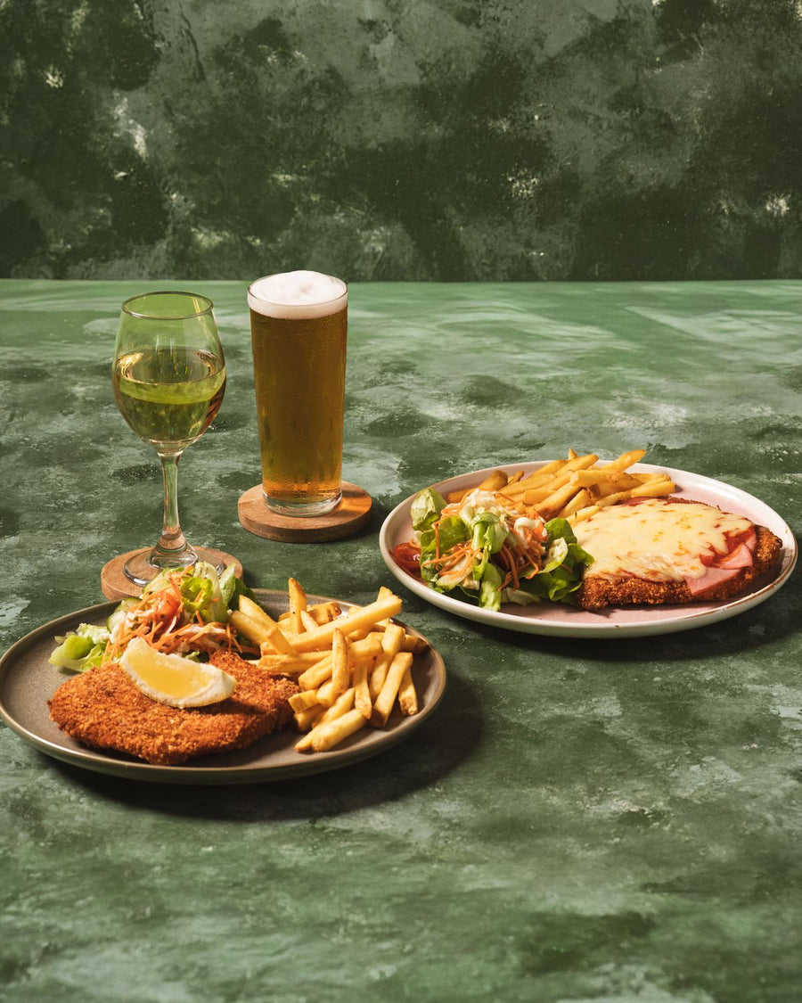 Chicken schnitzel and chicken parmigiana with chips and salad, with a beer and white wine