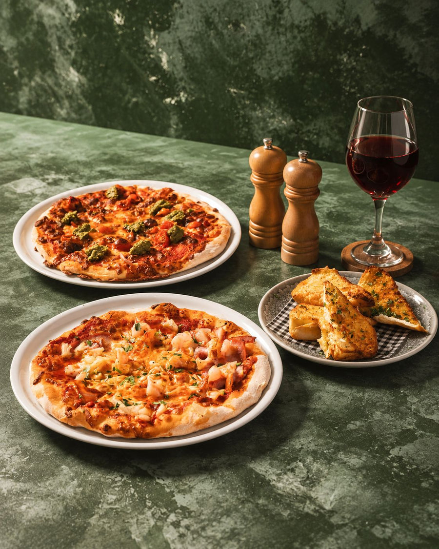 Two pizzas with garlic bread and a glass of red wine at the Parkwood Village bistro